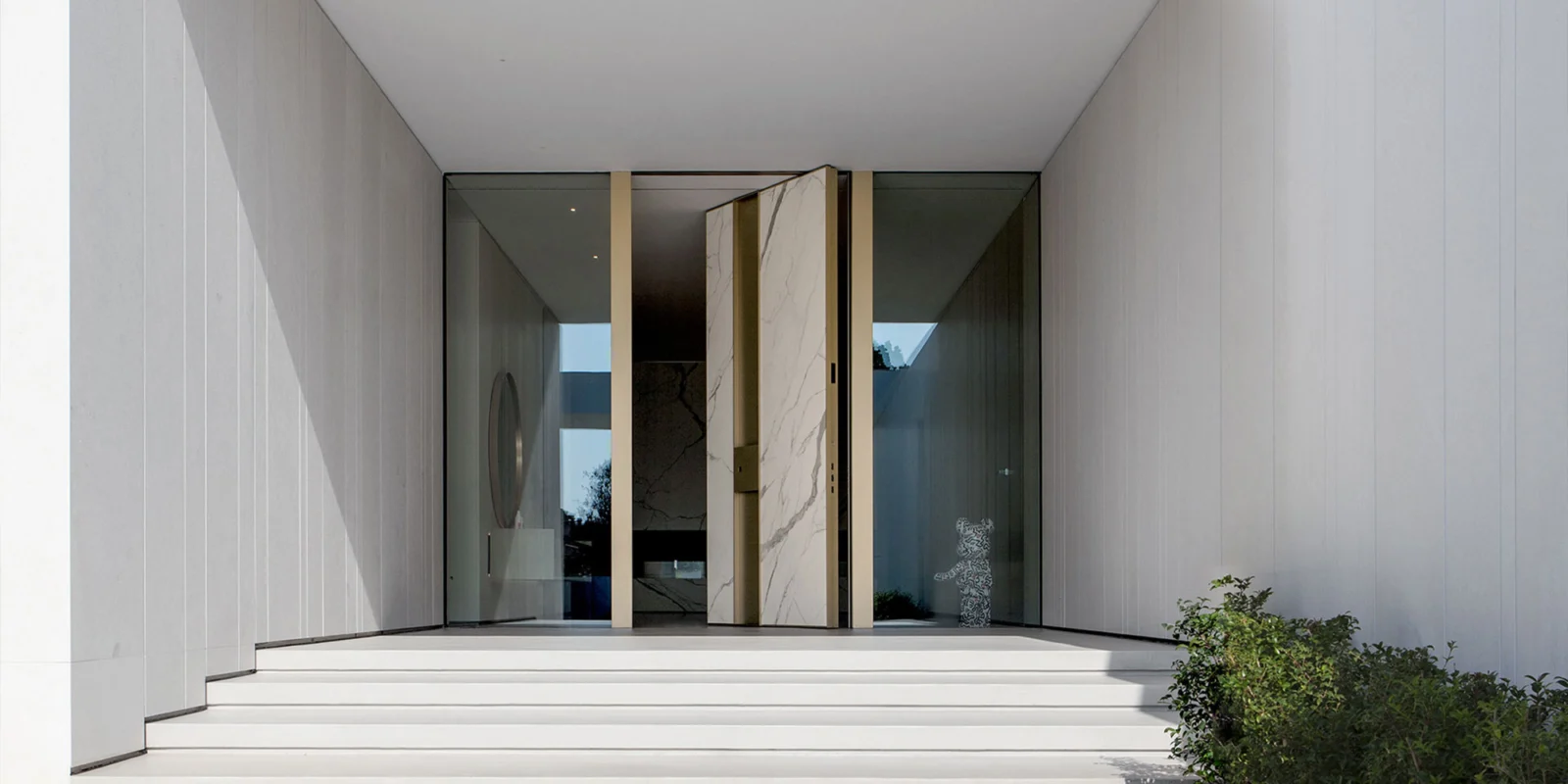 Oikos Synua pivot door with a coordinated architectural wall finish.